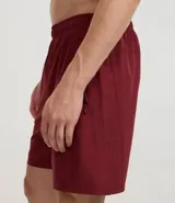 Bermuda deportiva gris con cintura elástica, cordón de ajuste, bolsillos con cremallera, recorte lateral con agujeritos y abertura en el bajo.