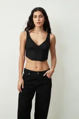 Top negro ajustado al cuerpo con escote en V profundo y tirantes anchos. Presenta un tejido texturizado, posiblemente encaje o jacquard, con un corte estilo corsé en la parte inferior.