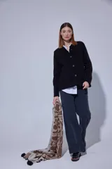 Saco de punto negro con textura acanalada, cuello redondo y cierre frontal con botones. Presenta un diseño clásico de manga larga y corte recto.