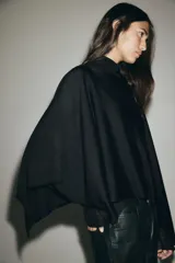 Capa de punto fino suave color negro, con escote bote y diseño amplio de caída fluida.