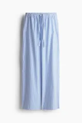 Pantalón de algodón de corte holgado, tiro alto, con cintura elástica fruncida y cordón fino para ajustar. Presenta piernas anchas y bolsillos laterales discretos. El diseño es a rayas verticales azules y blancas.