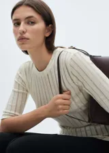 Camiseta de punto fino con diseño entallado, cuello redondo y mangas tres cuartos. Presenta una textura acanalada con sutiles rayas verticales.