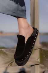 Zuecos tipo mule de cuero gamuzado negro, con plataforma forrada y detalle de tachas plateadas en el contorno. Presentan una plantilla con el logo bordado.