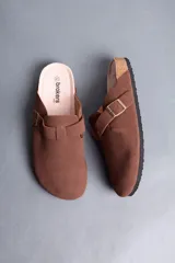 Sandalias estilo zueco de hombre, color marrón, con capellada cerrada, tira con hebilla ajustable lateral y suela de corcho y goma.