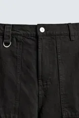 Pantalón cargo de corte relajado en color negro con efecto lavado. Presenta bolsillos laterales tipo cargo con solapas y cintas ajustables, bolsillos frontales y traseros, y detalles de argollas metálicas. Cierre frontal con cremallera y botón.