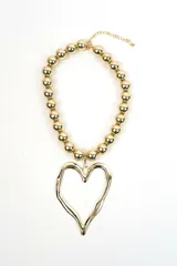 Collar dorado compuesto por cuentas esféricas metálicas y un gran dije colgante en forma de corazón con diseño orgánico y textura irregular.