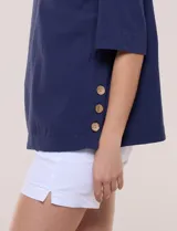 Blusa de algodón azul marino, con cuello redondo, mangas cortas amplias y detalle de botones en el lateral.