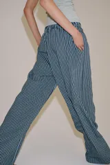 Pantalón de tiro medio con pierna ancha y cintura elástica, confeccionado en mezcla de viscosa con diseño de rayas verticales en tonos mostaza y marrón.