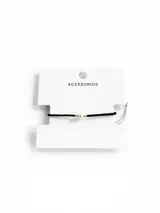 Pulsera minimalista de hilo negro con una perla central y pequeños detalles metálicos dorados a los lados.