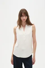 Musculosa de poliéster color blanco, con cuello en V y diseño holgado sin mangas.