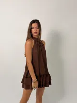 Vestido corto color marrón con textura plisada, diseño de cuello halter y falda con volados superpuestos.