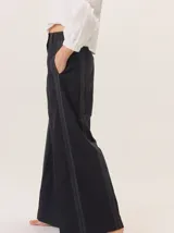 Pantalon de pierna ancha color azul marino, con costuras decorativas en contraste de color rojo y franjas laterales a tono. Cuenta con cintura alta, cierre frontal y bolsillos laterales.