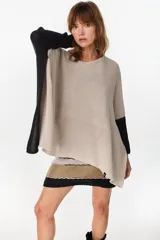 Poncho oversize de tejido de punto con hilos de lurex, color negro, con escote redondo y aberturas laterales en las mangas.