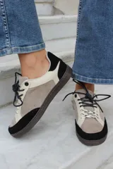 Championes de estilo urbano en combinación de tonos marrones y crema, confeccionados en gamuza y cuero. Presentan cordones jaspeados, suela de goma y detalle de logo bordado en el lateral.