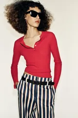 Pantalón de tiro alto y pernera recta con estampado de rayas verticales en tonos azul, marrón y beige. Incluye un cinturón delgado de color marrón oscuro con hebilla metálica dorada.