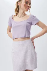 Top lila de escote cuadrado y manga corta con costuras verticales en el frente.