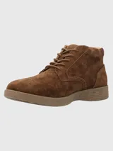 Bota de caña baja Hush Puppies, confeccionada en cuero gamuzado color marrón chocolate, con cierre de cordones al tono y suela de poliuretano con tecnología Spinal para mayor amortiguación y estabilidad.