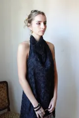 Vestido largo negro de corte halter con escote buche y espalda descubierta, de silueta relajada en forma de A. Cuenta con textura tridimensional de flores y relieves orgánicos.