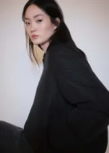 Chaqueta tipo bomber de diseño oversize en color negro, con cuello alto, cierre frontal de cremallera, bolsillos laterales y puños con elástico.