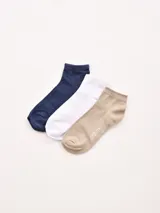 Pack de tres pares de medias tobilleras de tejido liso. Incluye un par azul marino jaspeado, un par blanco liso y un par beige con la palabra "GREGO" estampada.