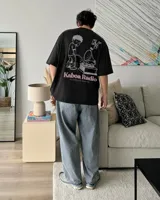 Remera oversize negra con diseño gráfico en la espalda que incluye la inscripción "Kaboa Radio" y un personaje ilustrado, de corte amplio y mangas cortas.