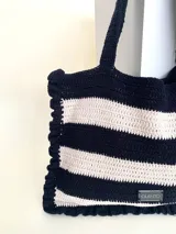 Bolso tipo tote tejido a crochet con hilo de algodón color marrón y crudo, con diseño a rayas horizontales y volados en los bordes.