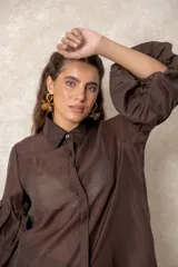 Camisa de organza blanca con cuello clásico, cierre frontal de botones y mangas tres cuartos abullonadas tipo globo con puños definidos.