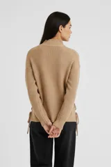 Sweater de punto de cuello alto, manga larga y diseño holgado, con detalle de flecos en los laterales.