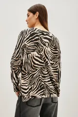 Sweater de punto con diseño de estampado animal print de cebra, cuello redondo y mangas largas con corte holgado.