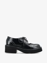 Zapato tipo guillermina con cordones, confeccionado en cuero negro con detalles de perforaciones estilo brogue. Presenta una suela de plataforma gruesa y tacón cuadrado.