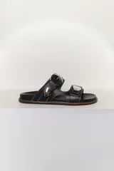 Sandalias negras de cuero con dos correas anchas con hebillas plateadas y pespuntes blancos.