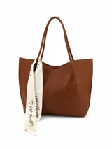Set de cartera tipo tote bag negra con textura granulada y sobre a juego con correa de muñeca. Incluye un pañuelo decorativo blanco con inscripciones negras atado a una de las asas.