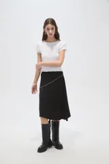 Falda midi negra de corte asimétrico, con detalle de costura diagonal decorada con pequeñas tachas metálicas.