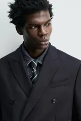 Blazer de corte regular fit confeccionada en tejido de lana italiana. Presenta cuello con solapas de pico, cierre frontal de botonadura cruzada, bolsillo de vivo en el pecho y bolsillos con solapa en la cadera.