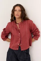 Chaqueta de lino color beige, de manga larga, con cuello redondo y cierre frontal de botones a presión con solapa.