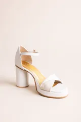 Sandalias de taco alto color blanco, con plataforma, taco cilíndrico, capellada con tira cruzada y tira ajustable al tobillo con hebilla dorada.