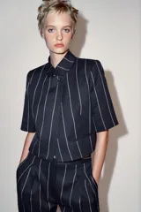 Chaqueta corta ZARA Woman Collection de diseño estructurado, color azul marino con patrón de rayas diplomáticas claras. Presenta cuello redondo mao, manga corta, falsos bolsillos de vivo en el delantero y cierre frontal cruzado con un botón.