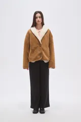 Chaqueta de gamuza sintética color camel con interior y cuello de corderito sintético color crema. Presenta un corte holgado, cierre frontal con botones y mangas largas.