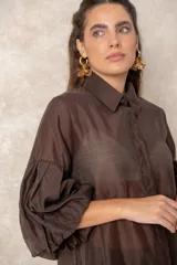 Camisa de organza blanca con cuello clásico, cierre frontal de botones y mangas tres cuartos abullonadas tipo globo con puños definidos.