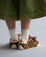Championes Converse Chuck Taylor Low con exterior de pelo con estampado animal print de leopardo, puntera de goma blanca, y doble juego de cordones en color rojo jaspeado y negro.