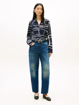 Camisa de Tommy Hilfiger de corte regular, confeccionada en sarga de viscosa azul marino con estampado abstracto de líneas blancas. Presenta cuello inglés, cierre frontal oculto con botones dorados, mangas largas con puños abotonados y detalle de plisado en la espalda.
