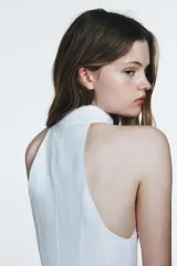 Vestido midi blanco, con cuello halter y falda con terminación en godets, lo que le da volumen y movimiento.