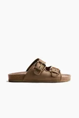 Sandalias color marrón topo, con dos tiras anchas ajustables mediante hebillas metálicas doradas. Presentan plantilla anatómica y suela con borde de corcho.