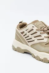 Zapatilla deportiva de estilo trekking con diseño técnico y urbano. Presenta una estructura combinada de paneles de malla y piezas de poliuretano, con sistema de cordones integrado y suela robusta con relieve para mayor estabilidad.