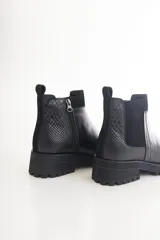 Botas Chelsea negras de cuero con elástico lateral, suela track y tirador trasero.