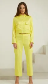 Chaqueta amarilla entallada al cuerpo, de manga larga, con cierre frontal de botones y bolsillos en el pecho.