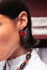 Aro tipo argolla de acero quirúrgico con dije colgante en forma de estrella color rojo, decorado con cristales hotfix.