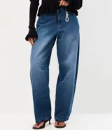 Pantalón baggy de jean azul con tiro medio, corte holgado, recortes en las rodillas y llavero decorativo con perlas y dije de corazón.