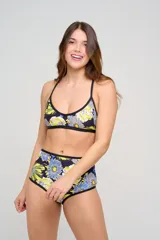 Corpiño de bikini estampado con diseño floral colorido en tonos fucsia, naranja y celeste, con ribetes negros y tirantes cruzados en la espalda.