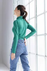 Polera verde esmeralda de cuello alto con detalle drapeado en el cuello, corte ajustado y mangas largas.